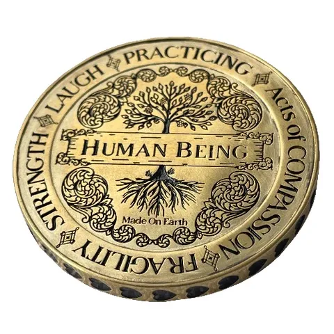 Detailed engraving on a gold "Human Being" coin pendant surrounded by virtues like Love and Strength featuring Ethereal font in use