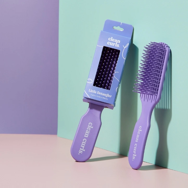 Purple hair detangler brush with its minimalist packaging box featuring Asikue font in use